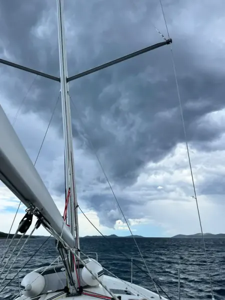View from the boat: the mast with the sails down, under dark storm clouds